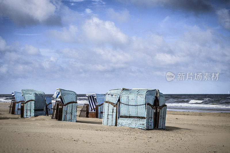 蓝色的沙滩椅子在Egmont aan Zee的北海海岸，荷兰在一个戏剧性的天空下